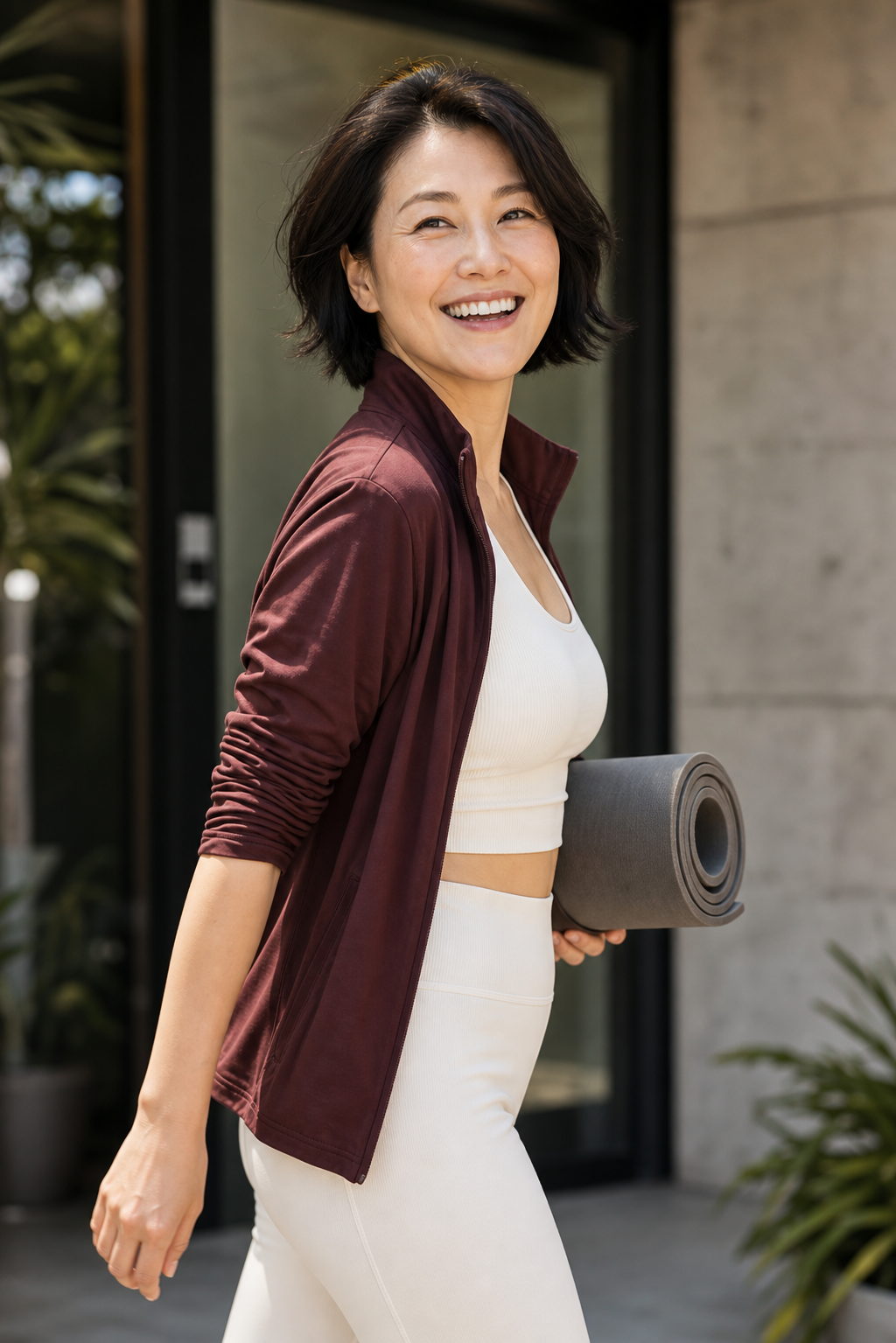 Happy woman carrying an exercise mat outside a wellness studio